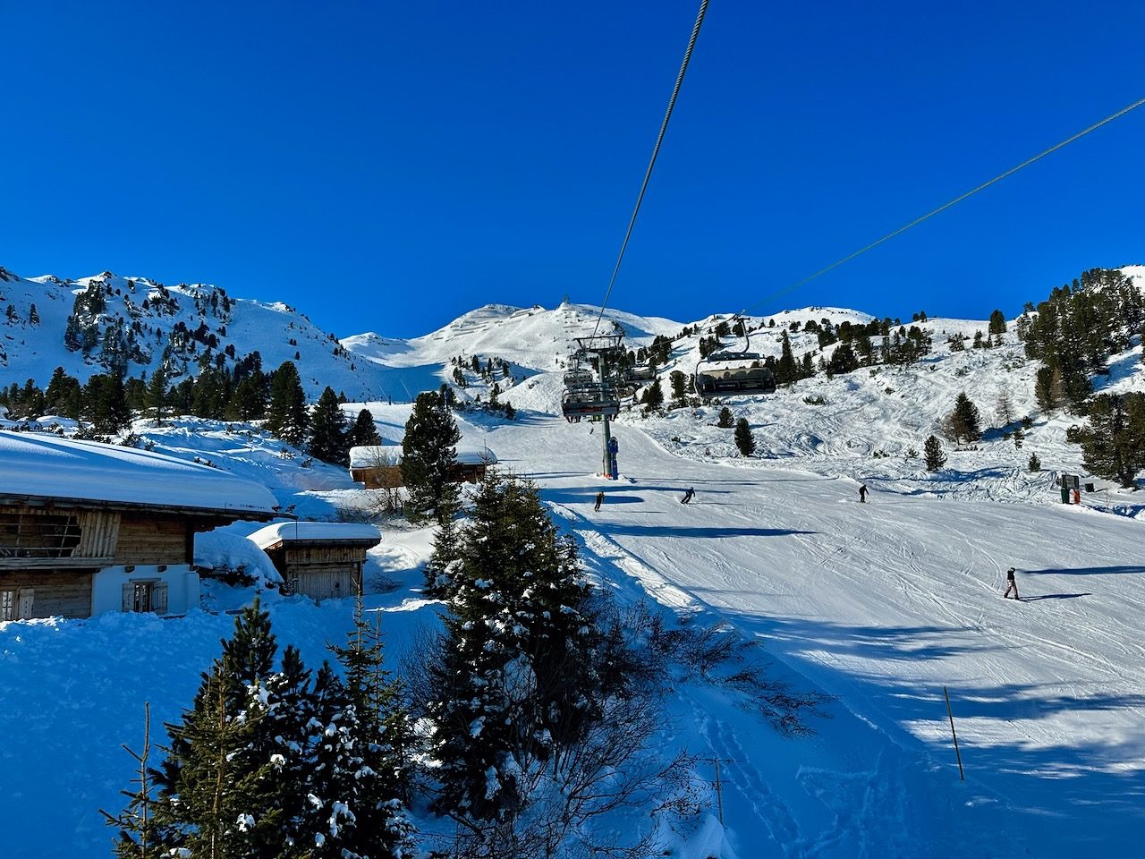 Sessellift über einer Piste mit Holzhütten